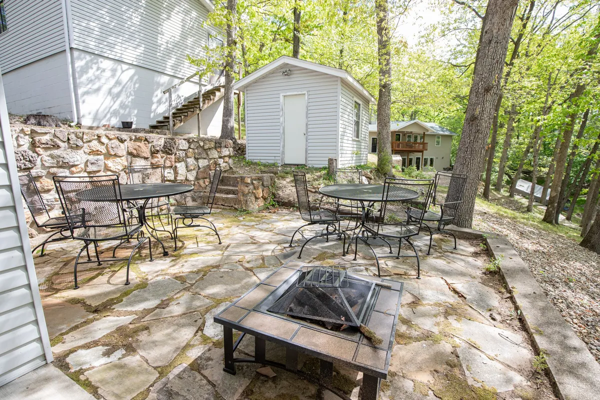 A cozy fire pit area is nestled among trees, with comfortable outdoor seating encircling the flames. The ambiance is warm and inviting, ideal for starlit conversations and evening gatherings by the fire.