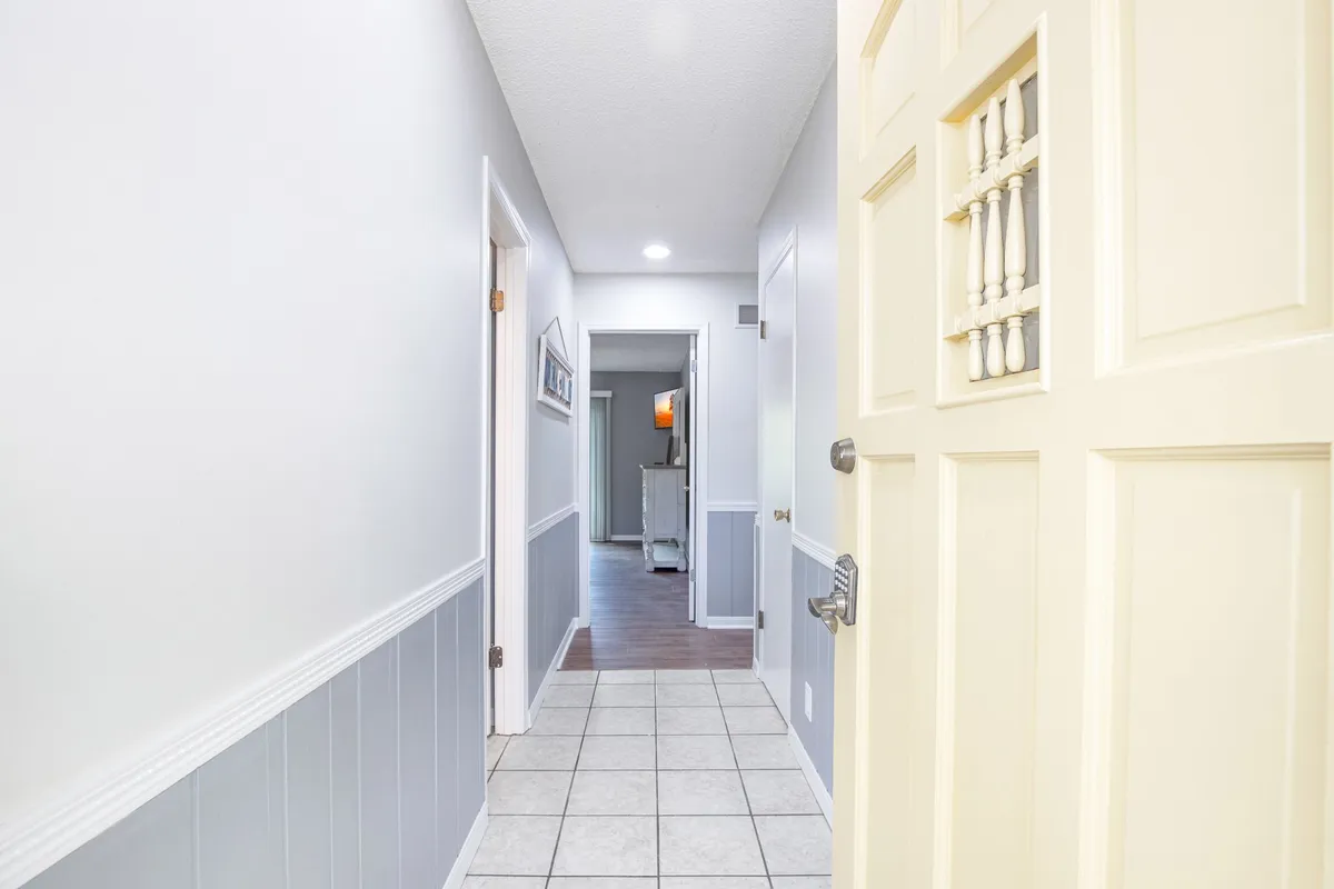 A warmly lit hallway and front door greet guests with inviting floor tiles and neat walls, illustrating the welcoming entry experience and secure access features. The tidy, uncluttered space suggests attention to guest comfort and ease from the moment of arrival.