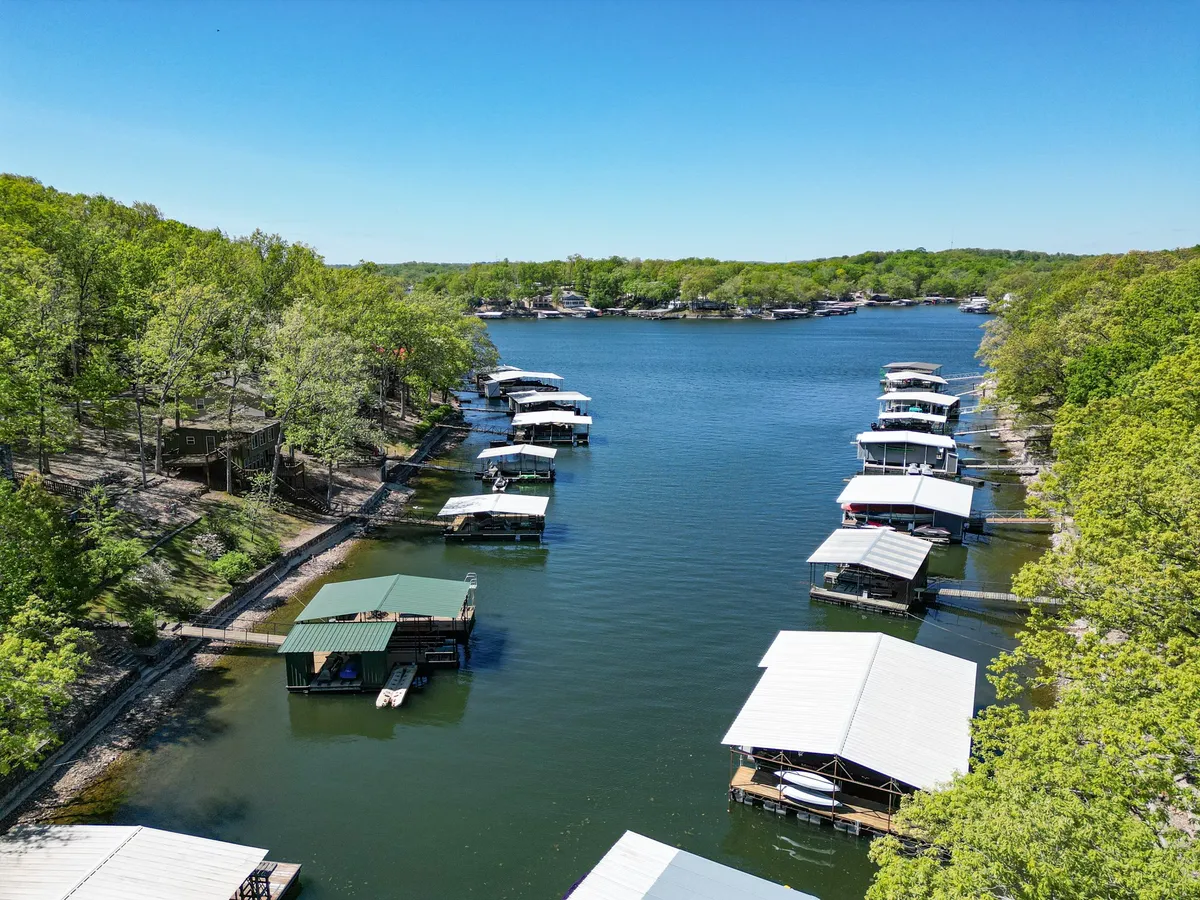 A tranquil dock scene with calm water, sturdy dock structures, and surrounding greenery. The peaceful atmosphere suggests opportunities for relaxing, gathering, or launching water activities.